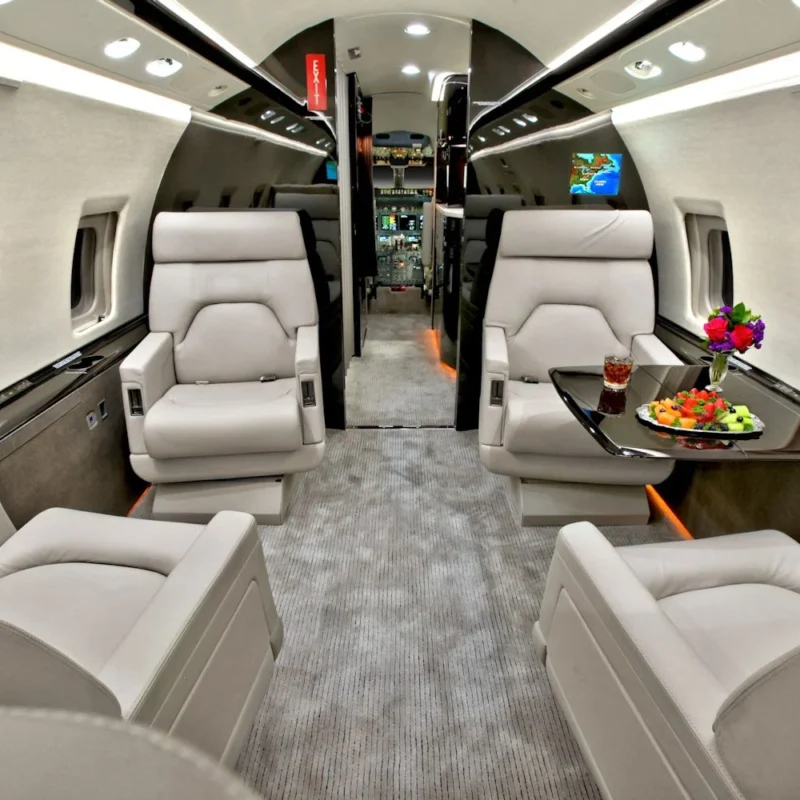 Private jet charter cabin with luxury seating and refreshments set on a table.