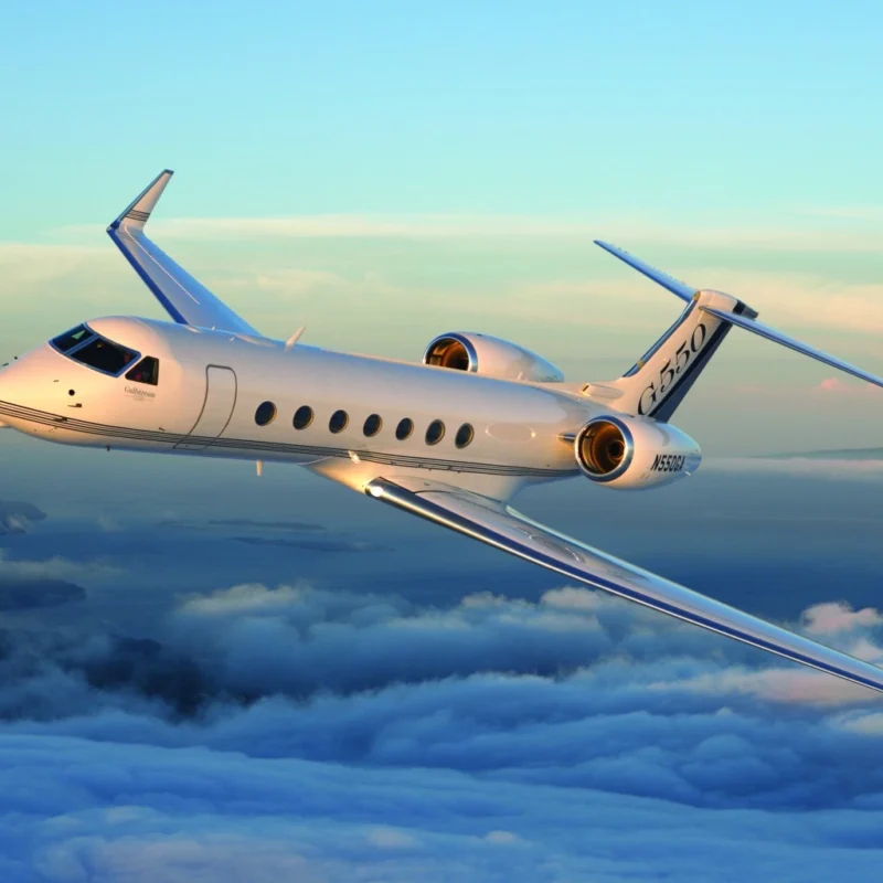 Private jet charter Gulfstream G550 flying above clouds at sunset.