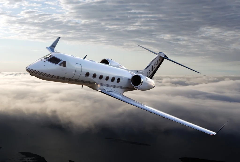 Jet charter guide featuring a sleek private jet flying over cloud cover at dusk