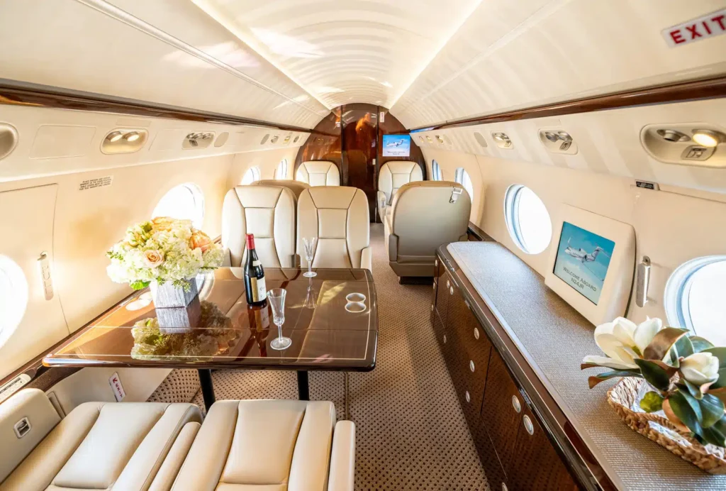 Luxury private jet cabin with elegant wood finishes, floral decor, and premium dining setup.