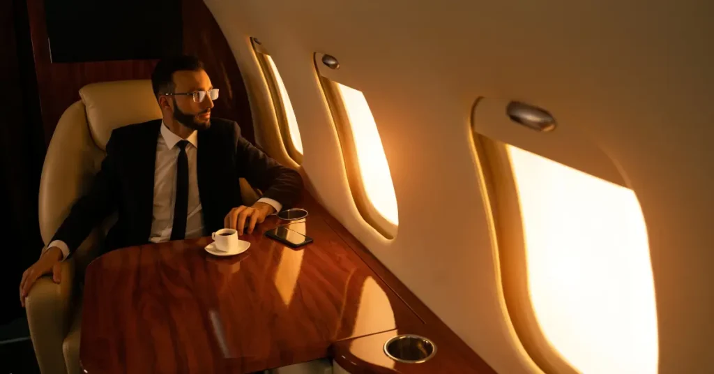 Private aviation passenger enjoying coffee while flying in a luxury jet during golden hour.