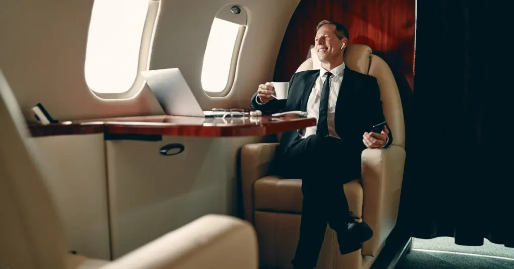 Private jet booking for executive traveler enjoying coffee and working on a laptop in luxury cabin.