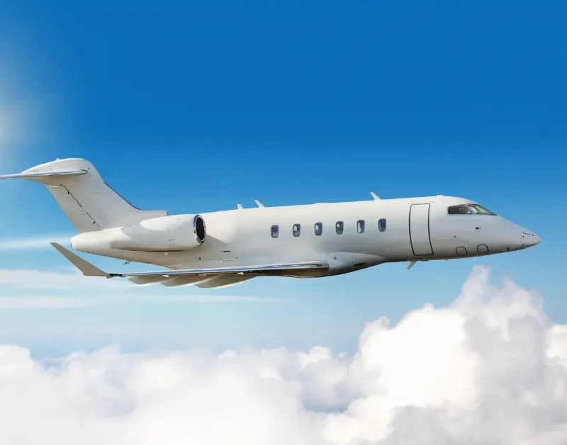 Private jet trips captured mid-flight above the clouds in clear blue sky.